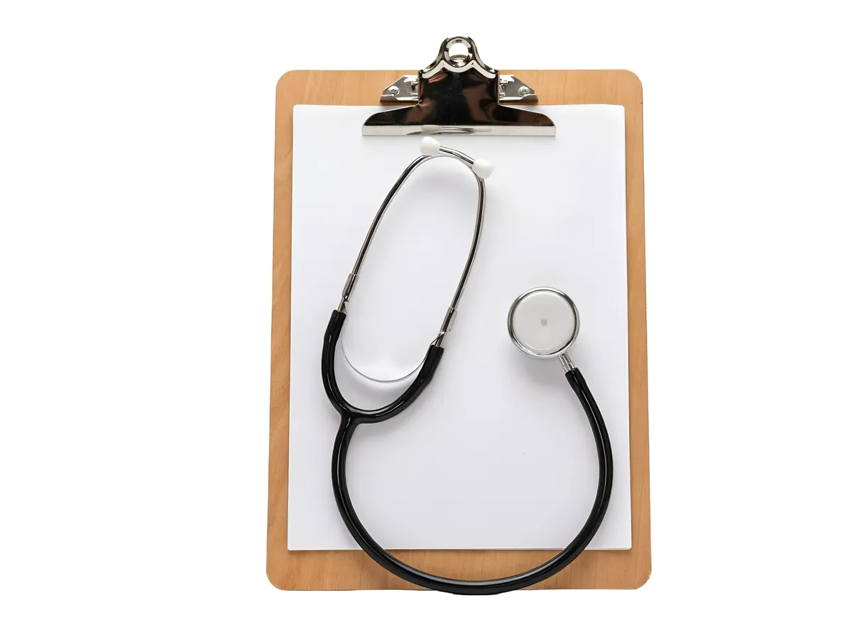 A stethoscope lying on a wooden clipboard with a blank sheet of paper — a stock picture