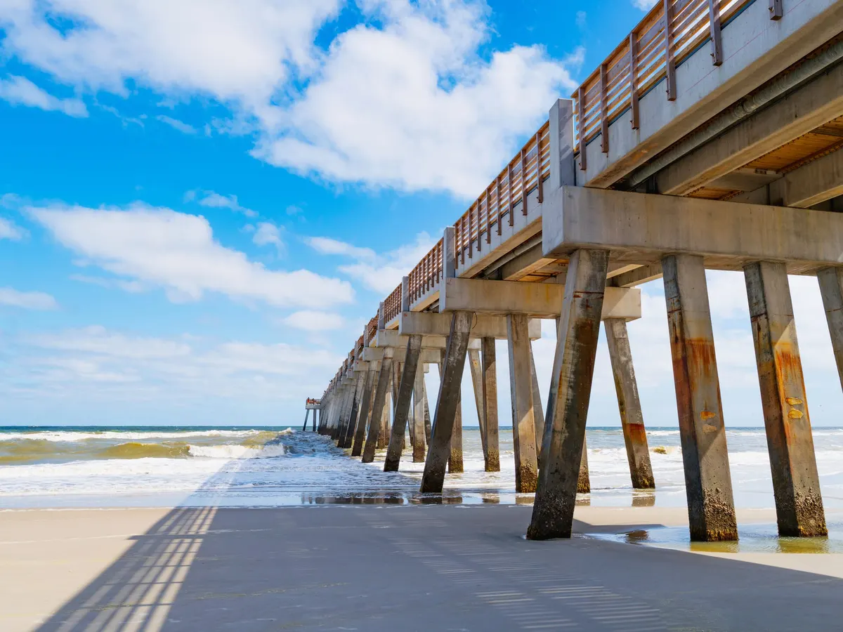 The Jacksonville Beach fishing pier stretching out over the surf on a sunny day with white clouds — a stock picture