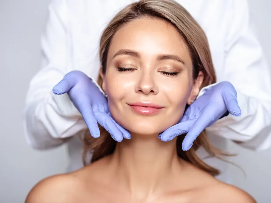 Woman with her eyes closed while a clinician in gloves gently holds her jaw