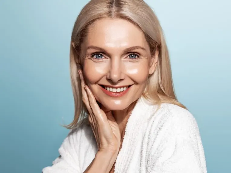 A woman smiling and showing the results of fillers for combating volume loss in the skin