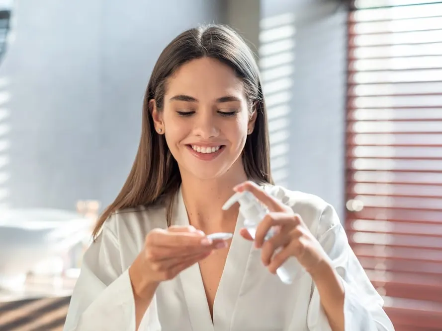 Woman applies skincare products to prevent and treat hyperpigmentation.