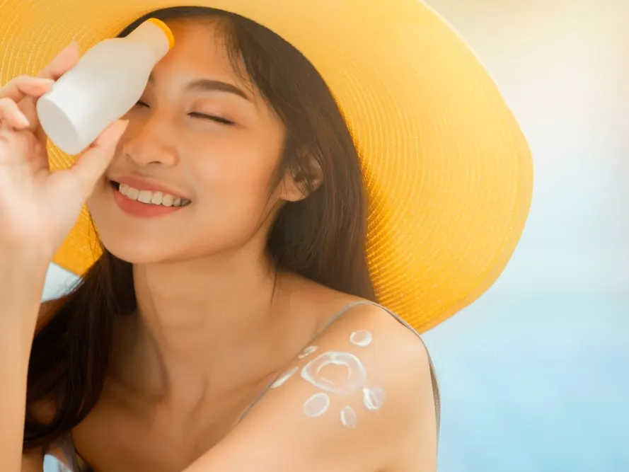 Young woman applying sunscreen to prevent sun damage in Jacksonville Beach, FL