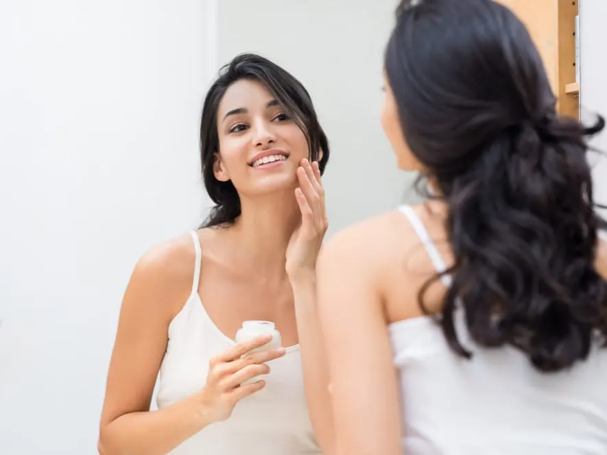 Woman putting lotion on beautiful skin before bed