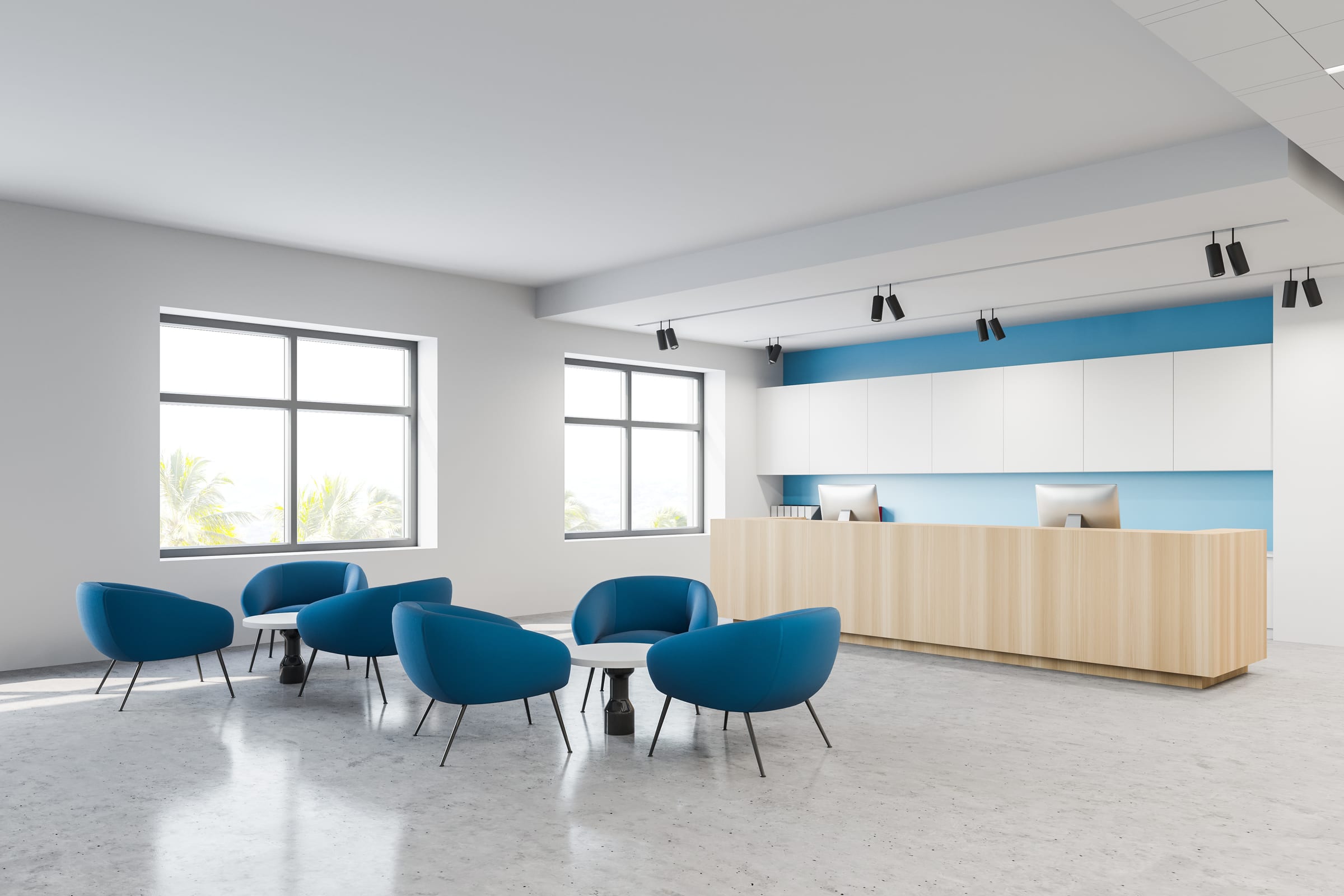 A bright clinic reception area with blue armchairs and a wooden front desk