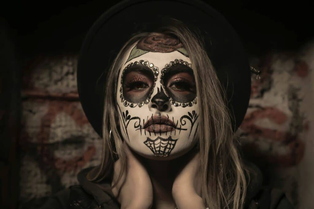 Woman in a black hat wearing skull-style Halloween face paint