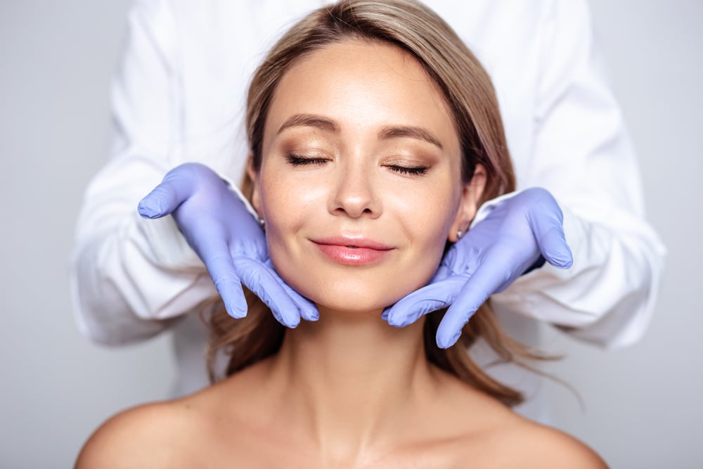 Woman with her eyes closed while a clinician in gloves gently holds her jaw
