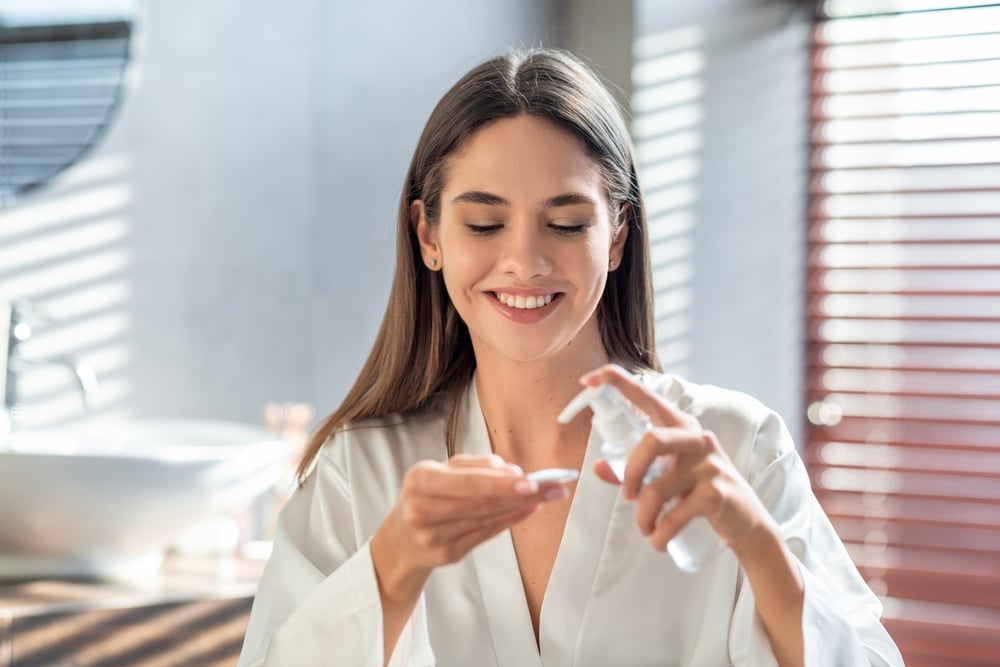 Woman applies skincare products to prevent and treat hyperpigmentation.