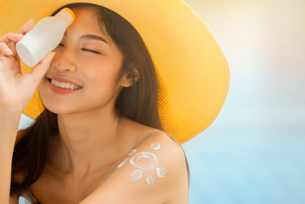 Young woman applying sunscreen to prevent sun damage in Jacksonville Beach, FL