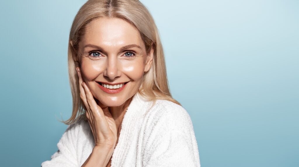 A woman smiling and showing the results of fillers for combating volume loss in the skin