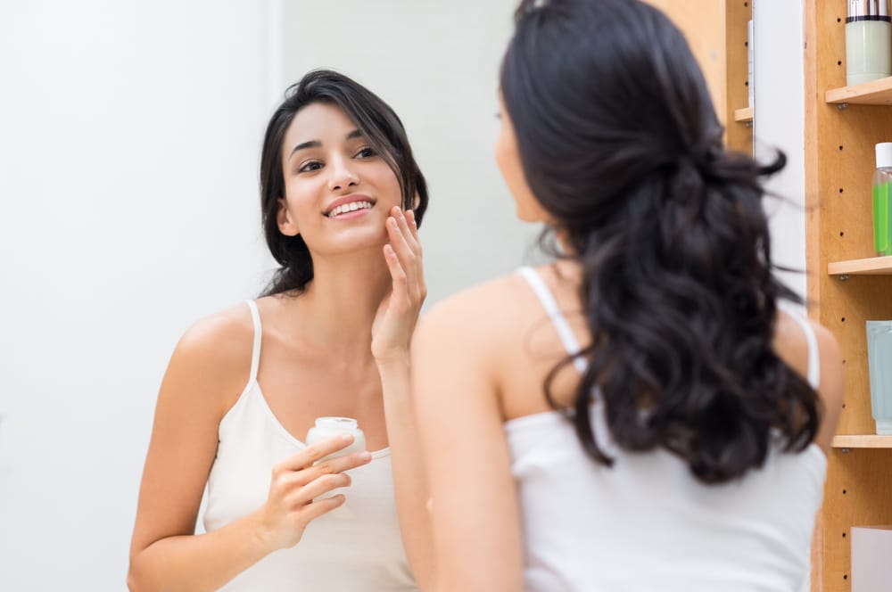 Woman putting lotion on beautiful skin before bed