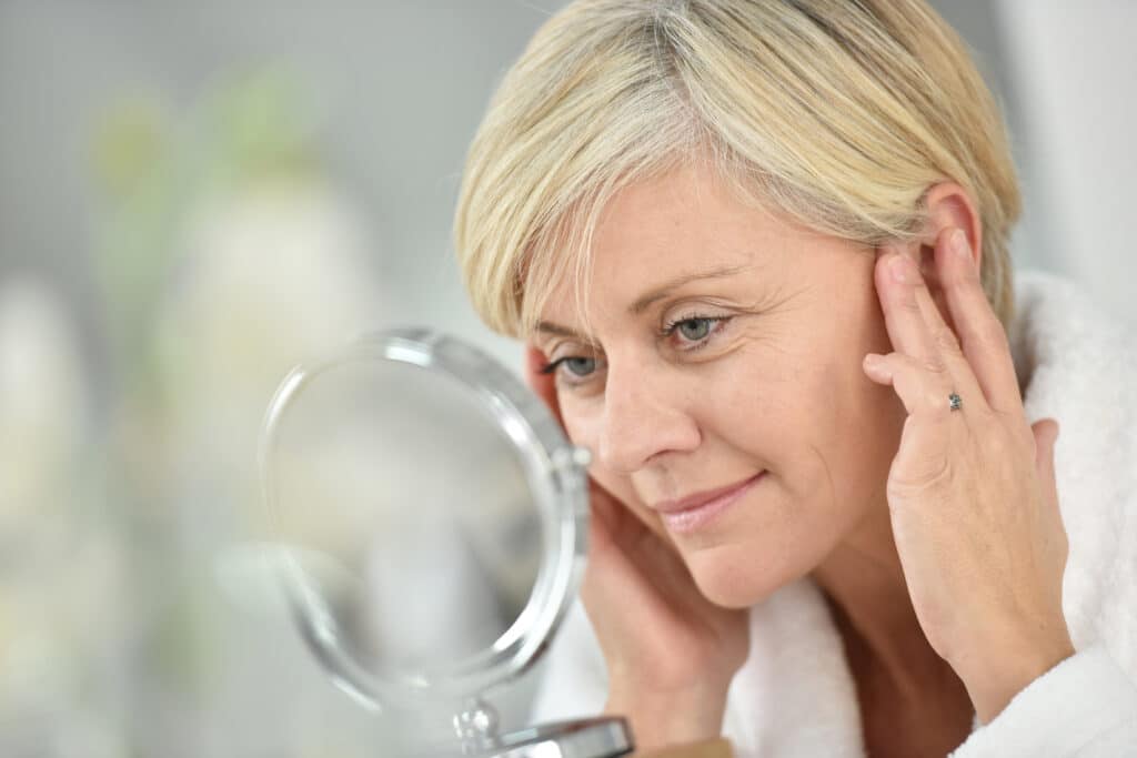 Mature woman looking at her skin in the mirror