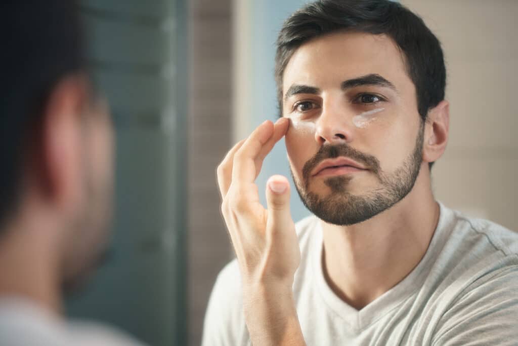 Man applying moisturizer as part of a daily skincare routine.